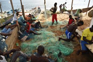 Small-scale fishermen mending fishing nets outside of Abidjan