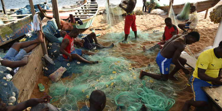 Small-scale fishermen mending fishing nets outside of Abidjan